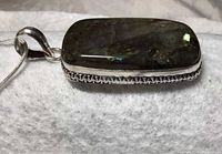 Close-up side view of the labradorite pendant showing the silver bezel and bail detail.