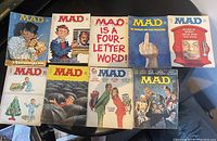 Top down view of 10 Mad Magazine issues showing front covers with various themes ranging from Christmas, parody of movies, and humorous cartoons.