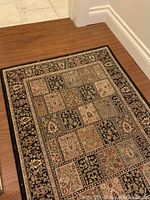 Dark tone small runner rug with black and beige colors and floral tile design on wood floor.