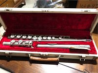 Full view of the antique flute disassembled into three sections inside the red velvet-lined carrying case showing condition and setup