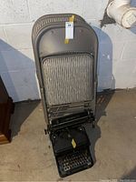 Four padded folding chairs stacked upright against wall with vintage Remington typewriter on floor in front.