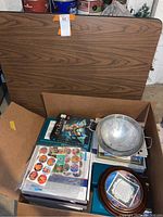Foldable card table, parts of the box and contents including strainers and Disney collectibles.