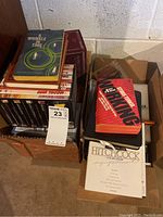 Two boxes filled with DVDs and books including Hitchcock collections and various titles