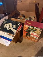 Initial overview photo showing multiple boxes containing Hardy Boys books, scripts, and the microscope box.