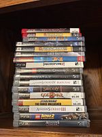 Stack of PlayStation 2 and PlayStation 3 game cases featuring various titles, showing titles and platform labels clearly.