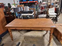 Front view of pine farmhouse dining table showing weathered top and turned legs