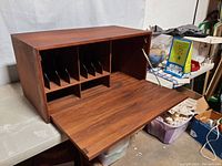 Front angle of the wall mounted desk with the drop down writing surface open and showing vertical file slots inside.