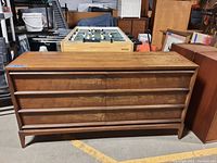 Front view of mid century modern wooden dresser with six drawers showing wood finish and scratches.