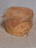 Side view of bamboo steamer baskets stacked and sealed in original clear plastic packaging showing natural bamboo material and round shape.