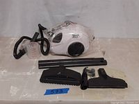 Steam Fast steam cleaner main unit, hose, and accessories arranged on table. Items appear new and unused.