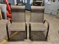 Front view of two matching outdoor patio sling chairs, showing brown metal frames and woven sling seats and backs.