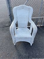 Front view of the white vintage wicker chair showing the arched high back and the overall condition of the wicker weave.