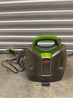 Front view of portable carpet cleaner showing green handle, Bissell logo, and clear tanks.