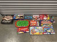 Photo showing an assortment of board games and game accessories including Scrabble, Twister, My First Magic Set, Monopoly, Cariboo, The Game of Life, and Operation Toy Story 3.