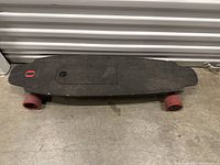 Full top view of the skateboard showing deck, grip, wheels, and battery compartment cover.