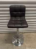 Front view showing the black leather tufted seat and backrest with chrome base.