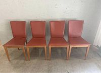 Front view of all four chairs side by side against a concrete wall
