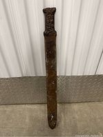 Full-length front view of rusted iron sword or bayonet against corrugated metal background