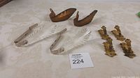 Full view of four antique curtain tie backs on fabric surface showing mixed materials and styles.