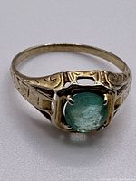 Front view of hand engraved ring with emerald stone on band