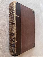 Front cover showing half leather binding with gilt lettering on spine and board with cloth exterior, signs of age and wear at edges and corners.