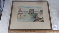 Full view of the framed watercolor painting showing the mat border and wooden frame placed on a patterned surface.