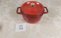 Top view of red Staub cast iron pot with lid and metal knob, showing condition and color