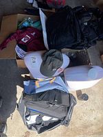 Image showing black backpacks, white torso mannequins, maroon jacket, and various water bottles inside boxes and bags.