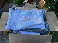 Box filled with multiple folded white Elevate t-shirts still in plastic packaging