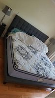 Angled view showing full bed frame, headboard, mattress, nightstands and lamp