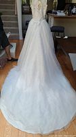 Photo showing the full wedding dress on a mannequin with long flowing organza skirt and extended train.