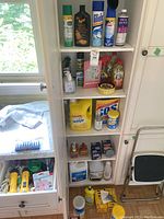 Cabinet shelves showing close-up of cleaning sprays, conditioners, hand sanitizer, insect spray, and housekeeping booklet.