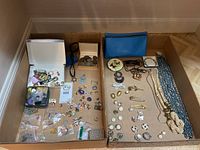 Wide view of the entire lot showing coins, pins, costume jewellery, jewellery boxes, necklaces, and fabric pouches.