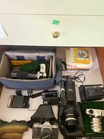 Assorted cameras, lenses, flashes, film boxes, charger and camera bag