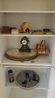 Shelf with ornate mantle clock, wooden coasters, barrel container, and stacked place mats.