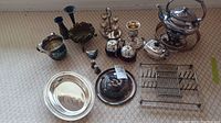 Full lot overview showing multiple silver plated items including teapots, serving tray, toast rack, butter dish, and candle holder.