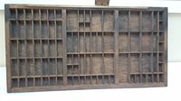 Full view of the antique printer's drawer showing multiple compartments and the overall wooden construction.