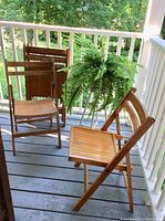 Five solid wood folding chairs arranged on a porch, showing overall condition and foldable design.