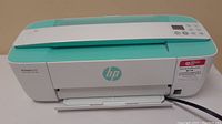 Front angled view of HP DeskJet 3760 printer showing turquoise top, control panel, and paper trays.
