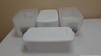 Nine translucent white Sterilite plastic storage containers with white lids organized in a group.