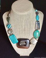 Front view of the choker necklace displayed on a beige linen bust stand showing the variety of materials and beads