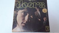 Front cover of The Doors LP showing close-up of Jim Morrison with the band and large yellow logo, plus a Gold Record award sticker.