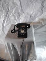Front view of vintage black rotary telephone showing dial and handset on cradle.