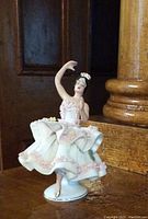 Front-right view showing delicate pose and details of lace skirt and crown.