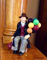 Front view of the vintage Royal Doulton Balloon Man figurine seated holding colorful balloons.