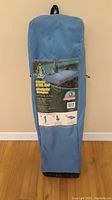 Folded Woods branded camp bed in blue carrying bag, showing the front of the bag and printed details.