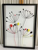 Full view of framed abstract floral print showing black, red, and yellow flower shapes with thin stems on white background.