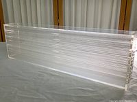 Side view of the clear rectangular plexiglass sculpture showing internal horizontal plastic rods.