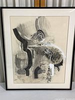 Framed abstract artwork with black metal frame and matting, showing entire piece hanging on wall.