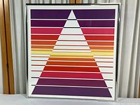 Front view of entire framed print showing silver metal frame, glass and colorful triangle design